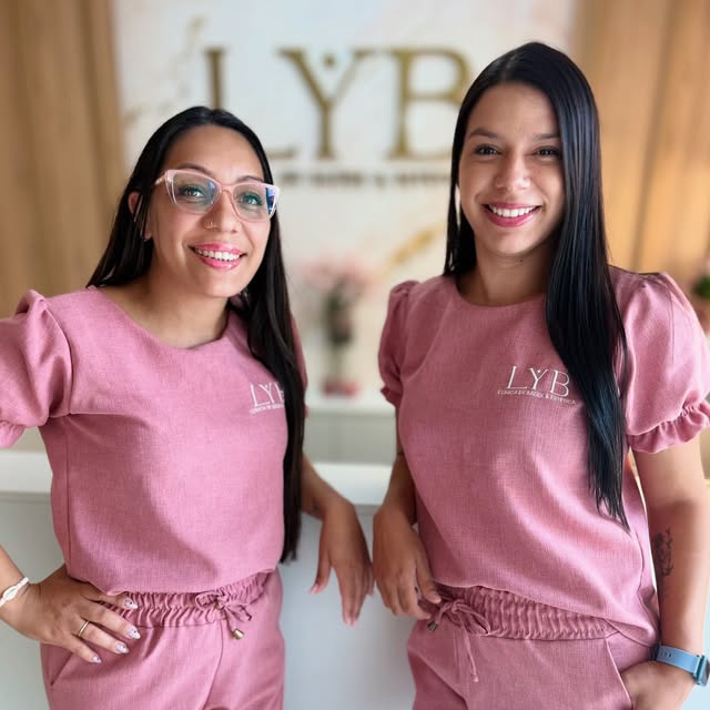 Equipe da LYB com uniformes rosa em frente ao logo da clínica